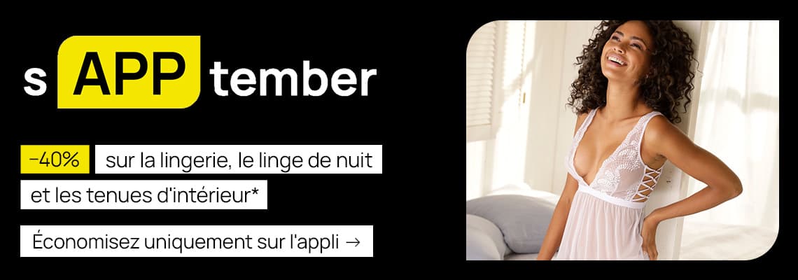 -40 % sur la lingerie, le linge de nuit et les tenues d’intérieur – Femme souriante en nuisette blanche, debout près d’un lit