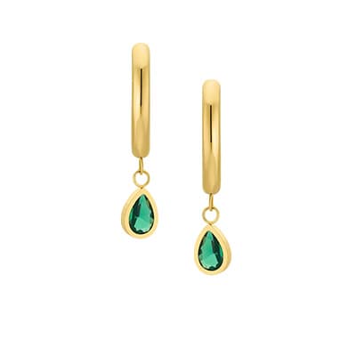 Person in hellem Outfit sitzt lässig auf weißem Block, trägt weiße Hose und grauen Pullover