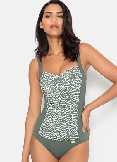 Femme debout en maillot de bain une pièce vert à motif imprimé blanc sur le devant, regard vers l’objectif