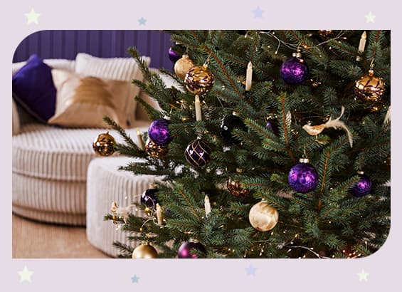 Weihnachtsbaum mit goldenen und lila Kugeln, goldenen Vögeln und Kerzen, im Hintergrund ein beige Sofa mit lila und goldenen Kissen