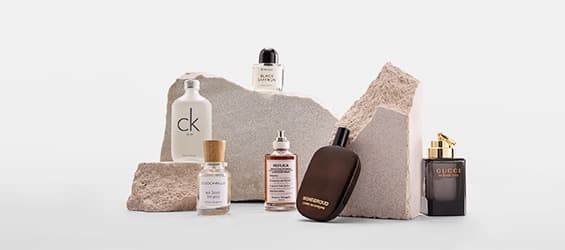 Collection de parfums variés, dont CK, Gucci et Tom Ford, posés sur des blocs de pierre