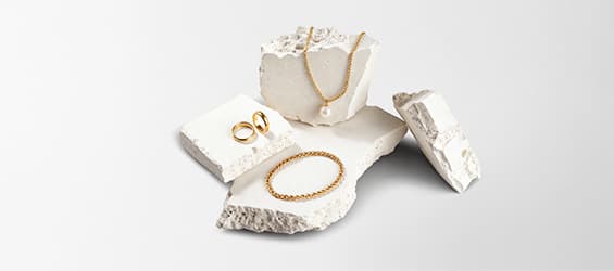 Bijoux en or – Collier avec perle, deux bagues et un bracelet sur des blocs de pierre blanche