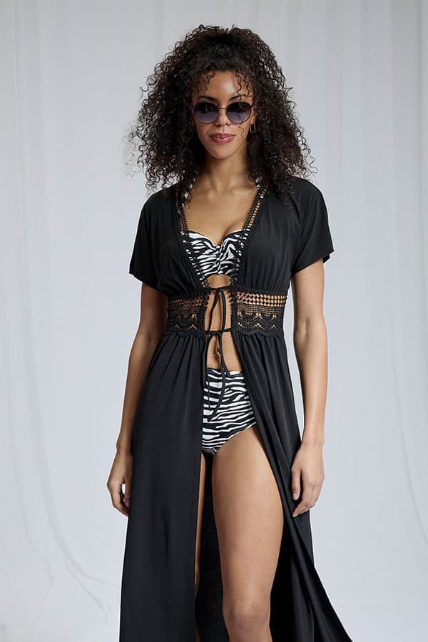 Femme vêtue d'une lingerie en dentelle noire transparente, avec de longues manches en dentelle et des attaches dorées, le visage flou