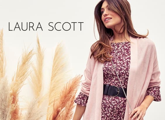 LAURA SCOTT – Femme debout en robe fleurie bordeaux et gilet rose, ceinture large noire, fond de plumeaux beiges