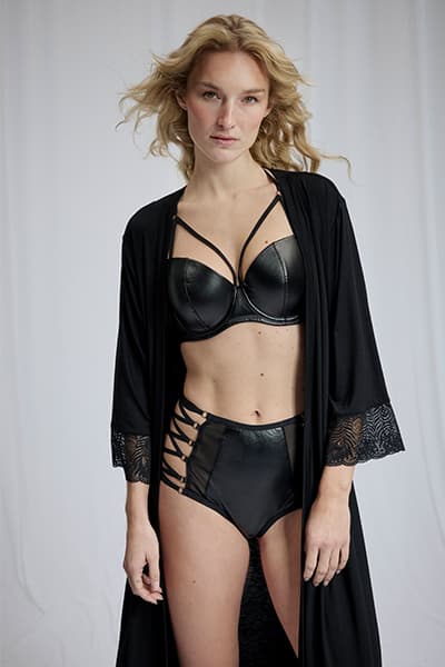 Femme debout en ensemble de lingerie noire à lanières et kimono long noir, face à l’objectif