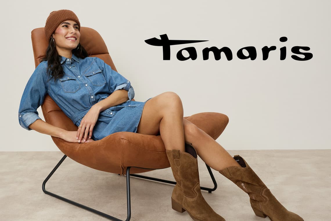 Tamaris – Femme assise dans un fauteuil, robe en jean, bonnet et bottes camel, regard vers la droite