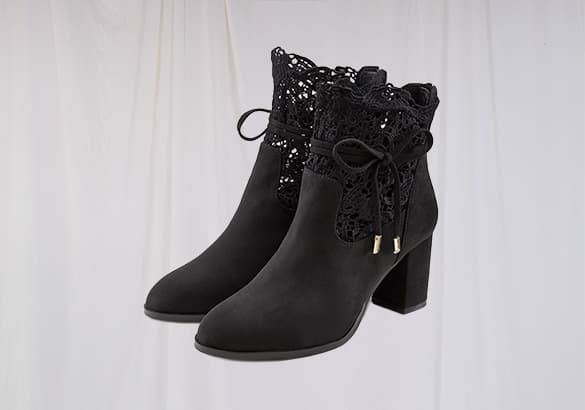 Schwarze Stiefeletten mit Spitze und Schleifen, vor weißem Hintergrund.