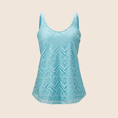 Frau in gemustertem Kleid und Weste steht vor einem Backsteingebäude mit großen Fenstern