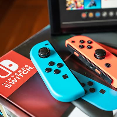 Zwei bunte Nintendo Switch Joy-Con-Controller liegen auf der Konsole, im Hintergrund der Bildschirm der Spielekonsole